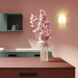 Elegante cocina con una **combinación de colores para cocina** audaz: rosa empolvado, verde azulado y detalles en burdeos y ocre. Flores rosas en un jarrón.