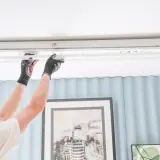 Persona con guantes cambia un tubo fluorescente por uno LED con cebador, mejorando la iluminación.