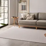Sofá gris y alfombra de diseño geométrico, mostrando diferentes tipos de alfombras para un salón moderno.