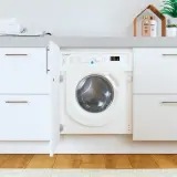 Lavadora Indesit con puerta abierta, lista para el lavado. El desague lavadora está oculto tras el mueble.