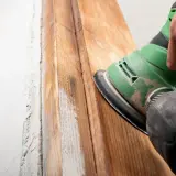 Mano lijando madera para quitar barniz. El proceso revela la veta natural.