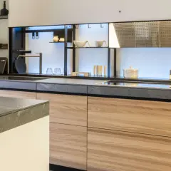 Encimeras resistentes al calor de piedra gris y gabinetes de madera clara en una cocina moderna.