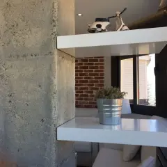 Ideas para decorar columnas dentro de la casa: estantes blancos flotantes con un modelo de Vespa y una planta en lata.