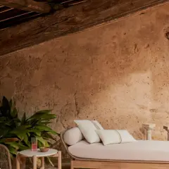 Un rincón acogedor para aprovechar buhardilla muy baja. Sofá, plantas y detalles rústicos bajo vigas de madera.