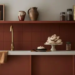 Encimera de cocina pintada en tono terracota, con grifería dorada y detalles decorativos.