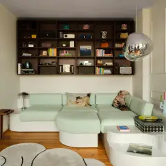 Estantería repleta de objetos y un sofá modular verde menta, demostrando cómo aprovechar espacios pequeños con estilo y funcionalidad.