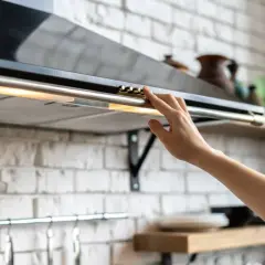 Mano ajustando controles de campana extractora decorativa, paso clave para su instalación.