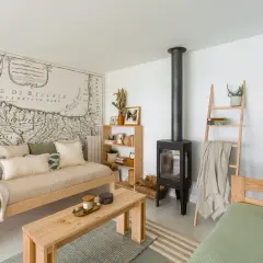 Acogedora sala de estar pequeña sencilla con sofá de madera, chimenea, estantería y un mapa antiguo en la pared.