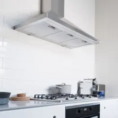 Cocina moderna con campana extractora de acero inoxidable, una de las muchas tipos de campanas extractoras. Encimera gris, vitrocerámica y nevera.