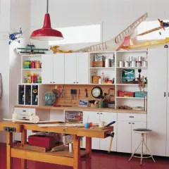 Un taller de bricolaje doméstico con maquetas de aviones, herramientas y estanterías llenas de materiales.