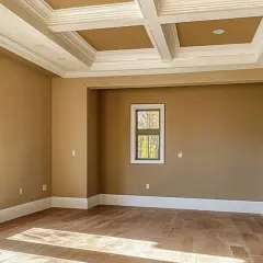 Habitación vacía con paredes color caramelo, techo artesonado blanco y suelo de madera. Ideal para empezar a pensar como pintar una habitacion.