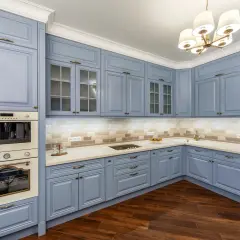 Cocina moderna con muebles de cocina pintados en azul pálido, encimeras claras y electrodomésticos integrados.