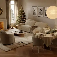 Acogedor **salón de Navidad** con chimenea encendida, árbol decorado, sofá, mesa puesta y una corona luminosa.