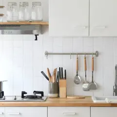 Una cocina pequeña y luminosa con encimera de madera, utensilios colgados y un fregadero.