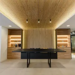 Revestimiento de pared de madera con iluminación cálida, estanterías y mesa de oficina moderna.