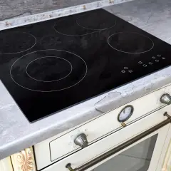 Placa de cocina vitrocerámica negra con cuatro zonas de calor y controles táctiles. Encimera gris piedra.