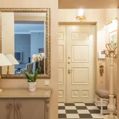 Ideas para pasillos estrechos como decorar: espejo dorado, consola, lámpara, orquídeas y suelo de damero.