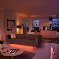 Salón y cocina modernos con iluminación ambiental. El color de la luz led cambia de naranja cálido a azul vibrante, creando una atmósfera acogedora.