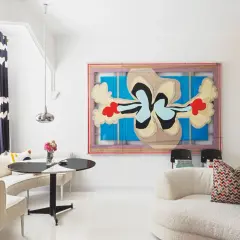 Un salón moderno con arte abstracto y muebles curvos. Sofás blancos texturizados y una mesa redonda negra y blanca crean sencillas salas pequeñas.