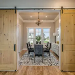 Dos puertas corredizas de madera rústica flanquean un comedor elegante, mostrando diferentes tipos de puertas.