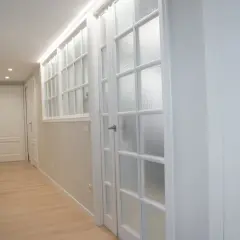 Pasillo con puertas blancas y vidrios emplomados, destacando la variedad de **colores de puertas** en un diseño moderno y luminoso.