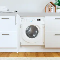 Lavadora Indesit con puerta abierta, lista para el lavado. El desague lavadora está oculto tras el mueble.