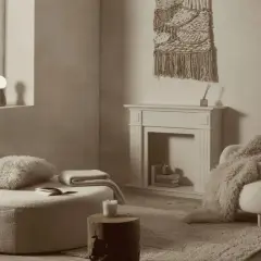 Acogedor rincón de lectura en una casa estilo nórdico, con un puf mullido, sillón con manta de pelo y chimenea decorativa.
