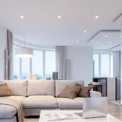 Salón moderno con sofá beige, mesa de centro y un techo pladur con focos empotrados. Ventanales curvos con vistas al mar.