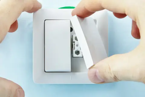 Manos instalan tapa en un interruptor doble Simon.