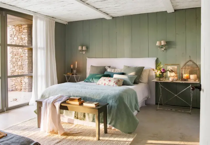 Habitación con paredes verde menta, cama con ropa de cama azul claro y cojines verdes. Inspiración de colores para habitaciones.