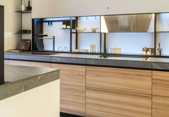 Encimeras resistentes al calor de piedra gris y gabinetes de madera clara en una cocina moderna.