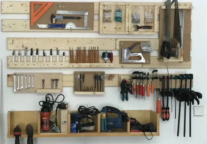 Organizar herramientas casero: un panel de madera con sierras, taladros, llaves, destornilladores y más, todo ordenado.