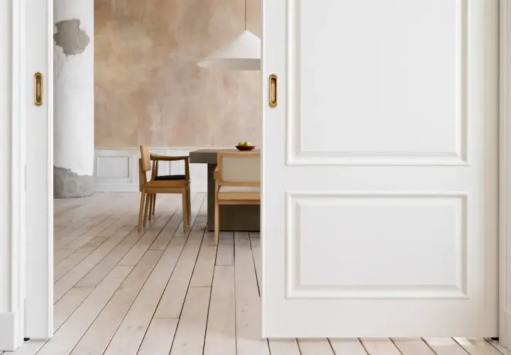 Puertas blancas y suelo de madera clara crean un ambiente acogedor. El diseño busca combinar suelo y puertas para una estética armoniosa.
