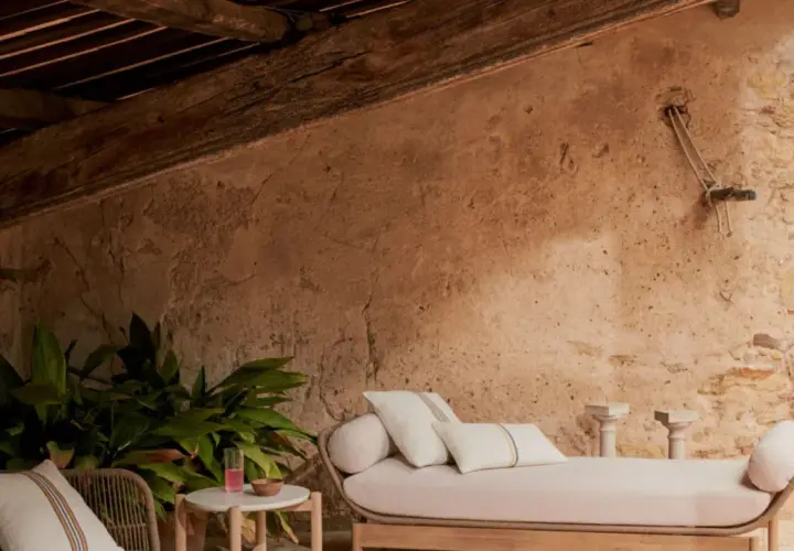 Un rincón acogedor para aprovechar buhardilla muy baja. Sofá, plantas y detalles rústicos bajo vigas de madera.