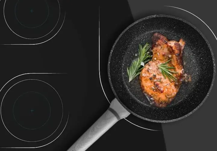 Un filete jugoso se cocina en una sartén sobre una placa de inducción. Aprende como limpiar la placa de inducción para mantenerla impecable.