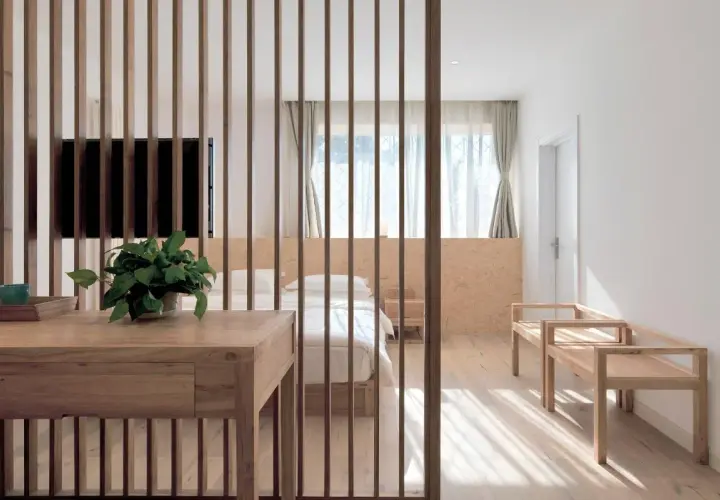 Elegante solución para separar ambientes sin obras, con un biombo de lamas de madera que delimita un dormitorio acogedor.