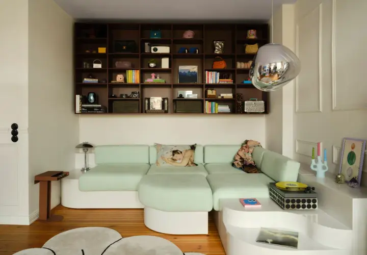 Estantería repleta de objetos y un sofá modular verde menta, demostrando cómo aprovechar espacios pequeños con estilo y funcionalidad.