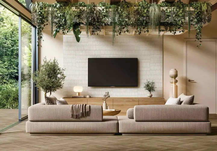 Un salón moderno con sofás beige, una pared con textura y plantas colgantes, reflejando las últimas tendencias en decoración de paredes.