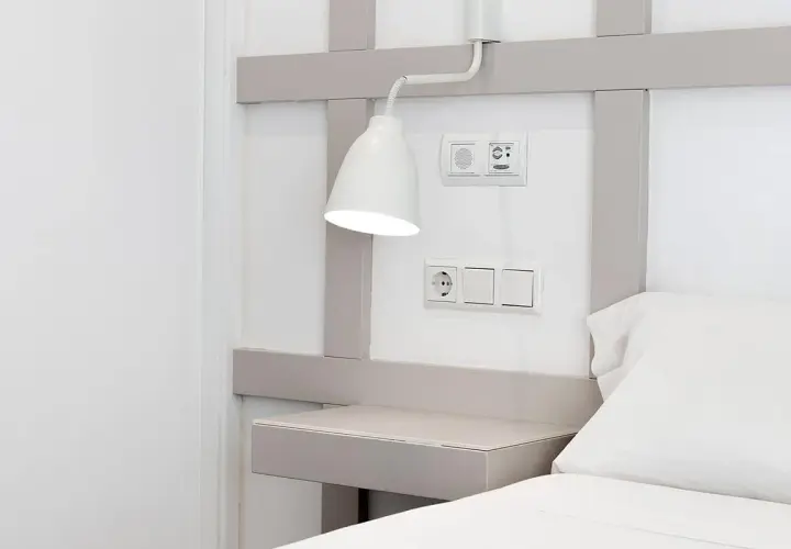 Interruptores y enchufe cerca del cabecero de la cama, con una lámpara orientable. La distancia entre interruptores cabecero cama es ideal para el control de luces.
