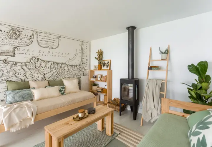 Acogedora sala de estar pequeña sencilla con sofá de madera, chimenea, estantería y un mapa antiguo en la pared.