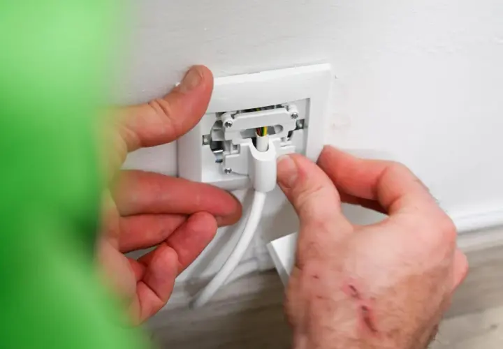 Manos conectando un cable a un enchufe para instalar enchufe de superficie.