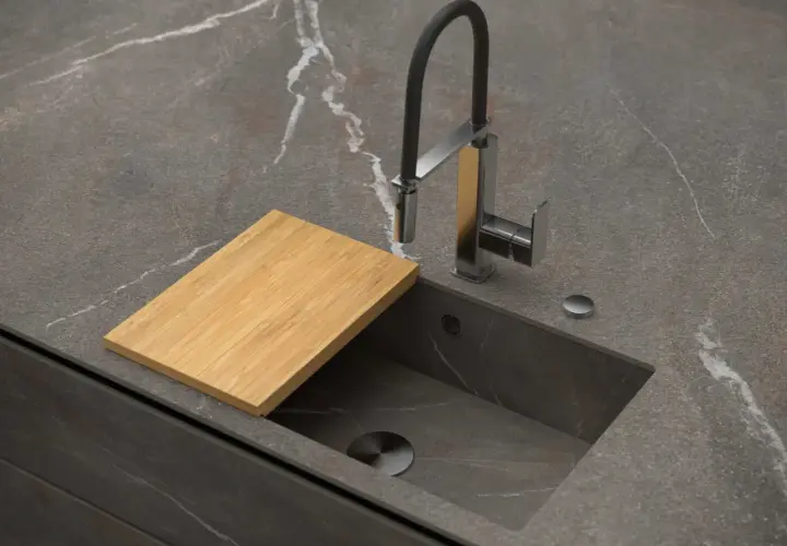Encimera de cocina moderna con fregadero integrado, grifo flexible y tabla de cortar de bambú. Explora los tipos de fregaderos.