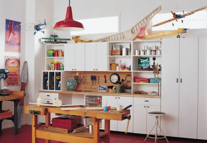 Un taller de bricolaje doméstico con maquetas de aviones, herramientas y estanterías llenas de materiales.