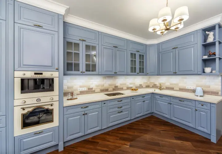 Cocina moderna con muebles de cocina pintados en azul pálido, encimeras claras y electrodomésticos integrados.
