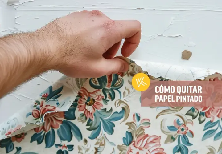 Mano retirando papel pintado floral de una pared blanca.