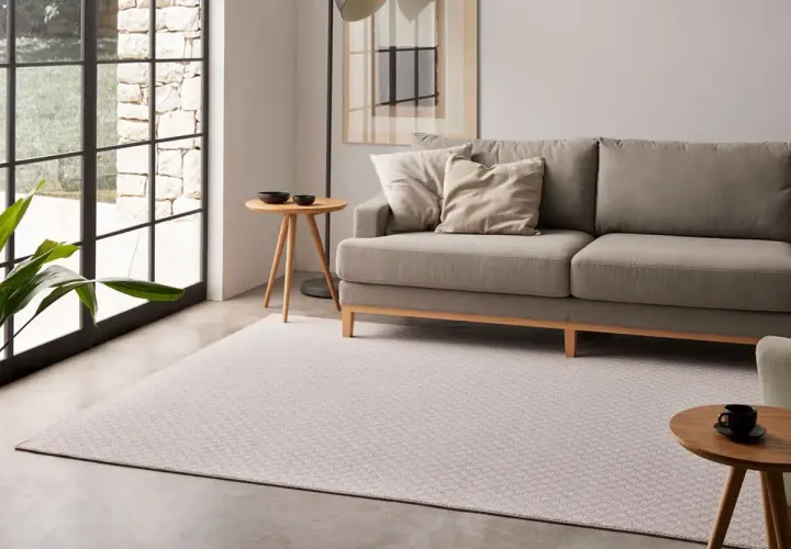 Sofá gris y alfombra de diseño geométrico, mostrando diferentes tipos de alfombras para un salón moderno.