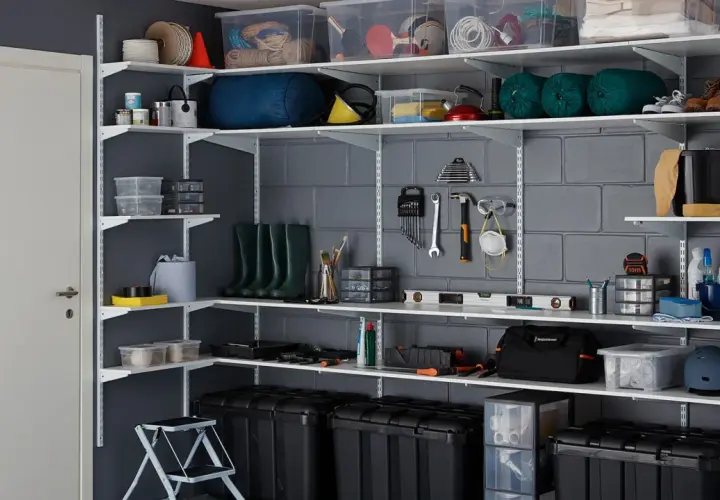 Estanterías metálicas con cajas, herramientas y botas. Una guía visual para saber como organizar un trastero de forma eficiente.