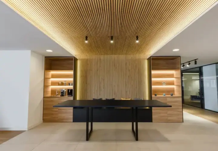 Revestimiento de pared de madera con iluminación cálida, estanterías y mesa de oficina moderna.