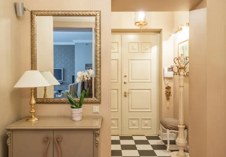 Ideas para pasillos estrechos como decorar: espejo dorado, consola, lámpara, orquídeas y suelo de damero.