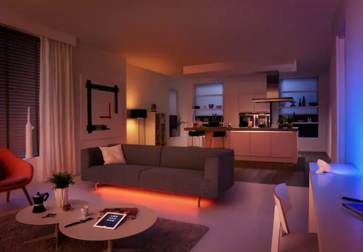 Salón y cocina modernos con iluminación ambiental. El color de la luz led cambia de naranja cálido a azul vibrante, creando una atmósfera acogedora.